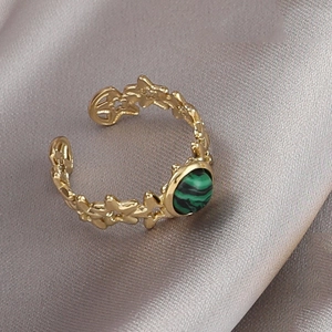 Détail d'une bague dorée avec motifs étoile lune et pierre de malachite verte