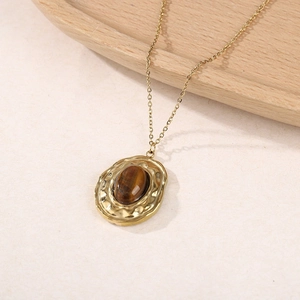 Détail du collier en acier titane avec pierre œil de tigre et pendentif martelé