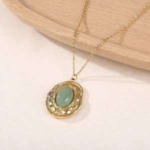 Collier vintage en titane doré avec pendentif ovale en pierre verte sur fond en bois