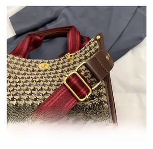 Macro detail of houndstooth tote bag featuring premium leather trim and adjustable striped strap