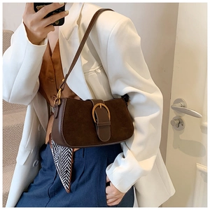 Detail of dark brown shoulder bag with metal buckle and decorative patterned silk scarf