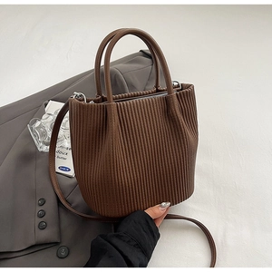 Detailed view of dark brown bucket bag featuring vertical pleated texture and leather straps