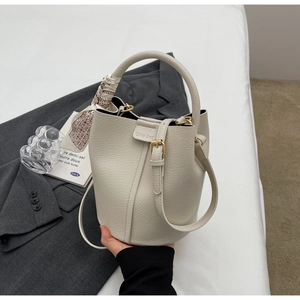 Detail of cream white leather bucket bag with silk scarf handle and brand logo