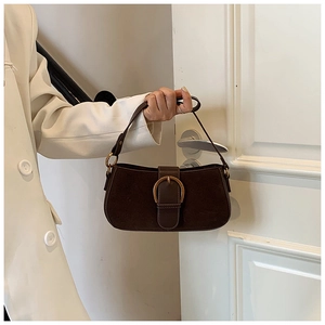 Detail of dark brown suede shoulder bag with a large golden horseshoe buckle