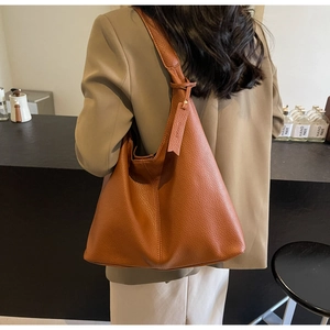Close-up of caramel brown pebble leather tote bag with wide strap for work