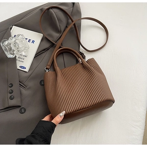 Detail of dark brown pleated bucket bag with vertical textured stripes and shoulder strap
