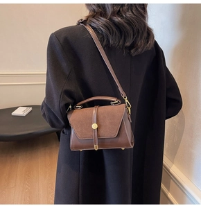 Close-up of brown patchwork handbag with gold metal clasp and adjustable shoulder strap