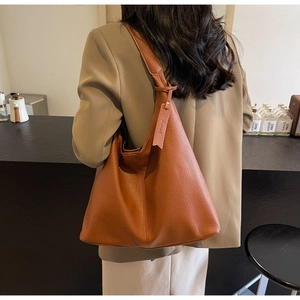 Detailed view of camel leather tote bag with lychee texture and hanging tag decoration