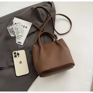 Close-up of brown pleated bucket bag with textured synthetic leather and a round base