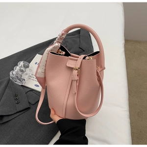 Detail of pink lychee leather bucket bag with floral silk scarf on top handle