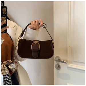 Detail of a dark brown baguette bag featuring a large gold horseshoe metal buckle