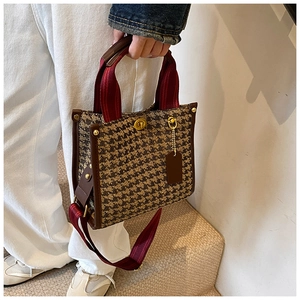 Detail of vintage houndstooth tote with leather trim, gold rivets, and twist-lock closure