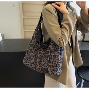 Side view of a large leopard print tote bag with black leather straps and hanging tag