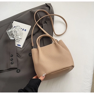 Detail of beige pleated bucket bag with vertical folds and detachable shoulder strap