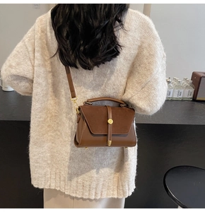 Brown vintage crossbody bag with suede patchwork and gold buckle worn by model
