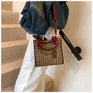 Detail of retro houndstooth tote bag with leather trim and decorative silk scarf handles
