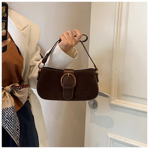 Detail of vintage dark brown suede baguette bag with gold metal buckle and leather strap