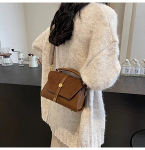 Close-up of brown vintage leather crossbody bag worn by a model in a cozy setting