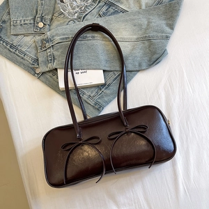 Vintage style brown underarm bag with decorative bows and glossy leather finish