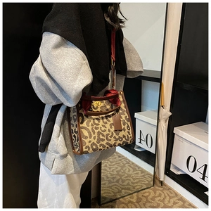 Detail of leopard print tote bag featuring a gold metal twist lock and leather trim