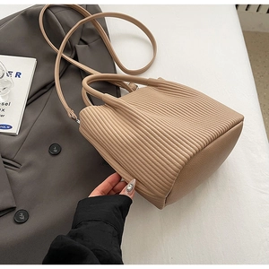 Detail of beige pleated bucket bag texture with shoulder strap on a grey suit jacket
