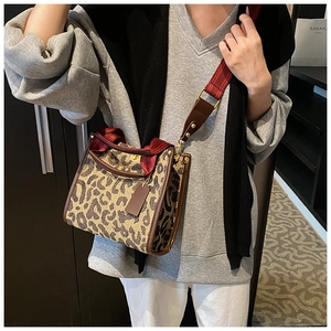 Detail of leopard print tote bag with brown leather trim and wide fabric shoulder strap