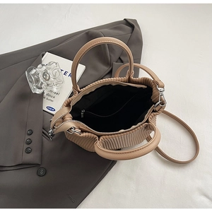 Interior detail of beige pleated bucket bag with black lining and adjustable shoulder strap