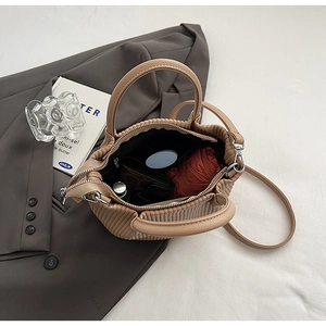 Detail showing spacious interior of beige pleated bucket bag with umbrella and cosmetics