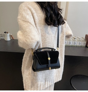 Crossbody bag in black smooth leather and suede with gold clasp in a stylish side view