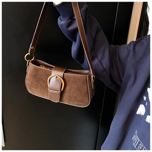 Detail of brown vintage baguette bag with matte texture and gold U-shaped buckle