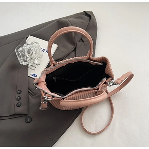 Detailed view of pink ruched bucket bag with cylindrical handles and interior zipper pocket