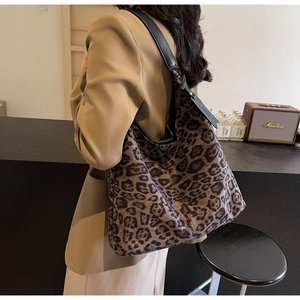 Detail of the leopard print tote bag with black leather shoulder straps and side tag