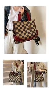 Detail of checkered tote bag featuring red fabric handles and adjustable shoulder strap