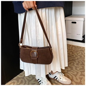Detail of vintage brown suede underarm bag with large bronze buckle on female model