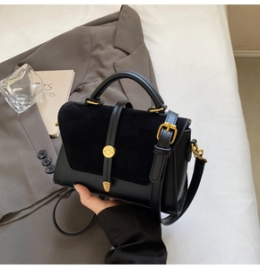 Detail of black crossbody bag featuring textured leather panels and gold-tone metal hardware