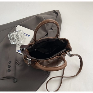 Detail view of the pleated brown bucket bag showing the interior compartment and lining
