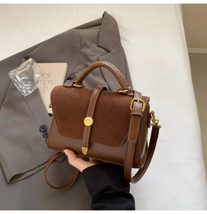 Detail of vintage brown leather handbag with suede patchwork and gold buckle closure