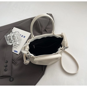 Detailed interior of the beige pleated bucket bag showing the zipper pocket and lining