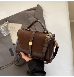 Detail view of dark brown vintage crossbody bag with gold round clasp and retro texture