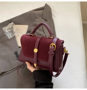 Detail of wine red crossbody bag featuring suede patchwork and gold metal hardware buckle