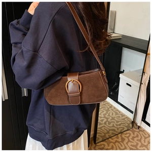 Brown vintage suede underarm bag with metal buckle detail shown in use on shoulder