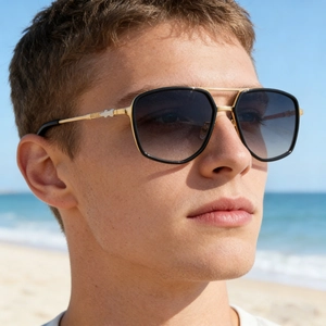 Close-up of golden metal double-bridge sunglasses with gradient lenses on beach