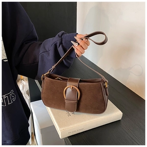 Detail of dark brown suede baguette bag with golden horseshoe buckle and leather strap