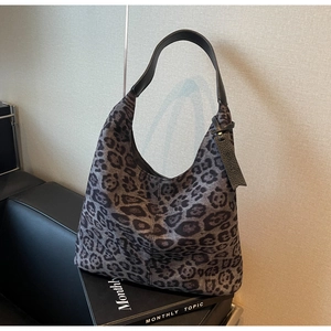 Close-up of hobo bag with grey leopard print and black leather strap on books