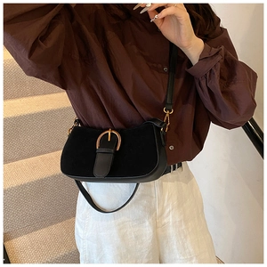 Detail of black vintage underarm bag with gold horseshoe buckle on model's shoulder