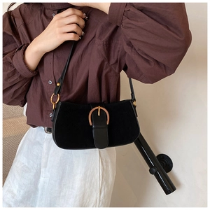 Detail of vintage black suede underarm bag with gold horse-bit buckle on female model