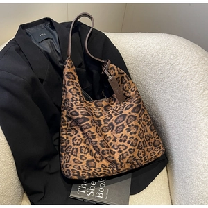 Detailed close-up of leopard print tote bag fabric and soft brown leather shoulder strap