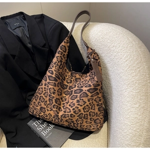 Close-up of leopard print tote bag placed on white sofa next to black blazer and book