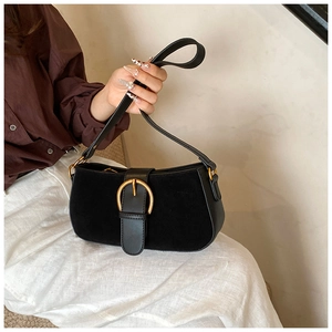 Macro detail of black suede and smooth leather textures with a golden round buckle