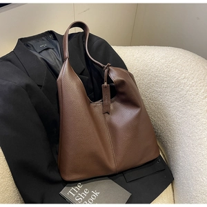 Detailed view of dark brown pebbled leather tote bag placed on a chic black blazer